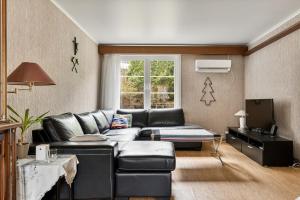 a living room with a black leather couch at Tysso Apartment in Tveit