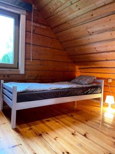 a bed in a log cabin with a window at Country side/Kaštonų alėja - Sodyba in Sudeikiai