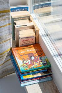 une pile de livres assis sur une étagère à côté d'une fenêtre dans l'établissement Sunny Seaside Apartment with Terrace & Parking by Noclegi Renters, à Jastrzębia Góra