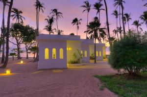 una casa sulla spiaggia con palme di Diamonds Mapenzi Beach a Kiwengwa