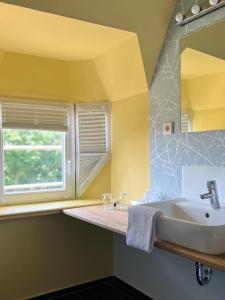 ein Bad mit einem Waschbecken und einem Fenster in der Unterkunft Stuckhotel Fettehenne in Ratingen