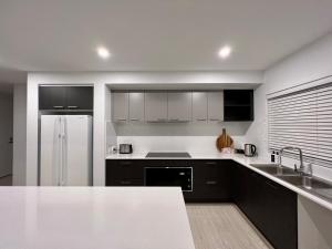 a kitchen with black and white cabinets and a refrigerator at Sun and Sea Holiday Home in Cowes