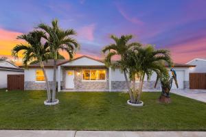 ein Haus mit zwei Palmen davor in der Unterkunft Fantasy Resort OMG PoolWaterfall outdoorKitchn Gym in Lake Worth