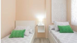 1 dormitorio con 2 camas y almohadas verdes y blancas en Torremolinos Bajondillo beach, en Torremolinos