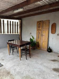 einen Holztisch mit zwei Stühlen und einer Holztür in der Unterkunft Graziosa stanza campidanese Su segundu in Oristano