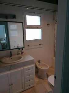 ein Badezimmer mit einem Waschbecken, einem WC und einem Spiegel in der Unterkunft Casa con piscina privada in El Puerto de Santa María