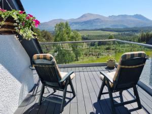 two chairs on a balcony with a view of mountains at Wee Neuk in Spean Bridge