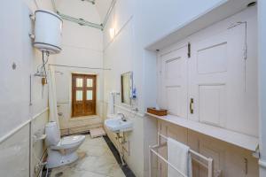 a white bathroom with a toilet and a sink at Neemrana's - Piramal Haveli in Bagar