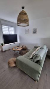 uma sala de estar com um sofá verde e uma mesa em Entre terre et mer em Saint-Brévin-les-Pins
