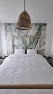 Un dormitorio con una gran cama blanca con un colgante en Entre terre et mer en Saint-Brevin-les-Pins