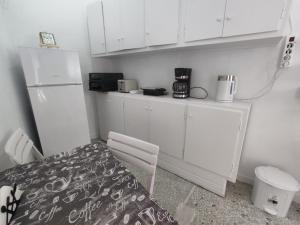 uma cozinha com armários brancos, uma mesa e um frigorífico em Cozy flat em Atenas