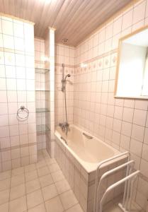ein weiß gefliestes Bad mit einer Badewanne und einem Spiegel in der Unterkunft Maison Encantalou 