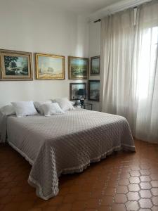 ein weißes Schlafzimmer mit einem großen Bett und einem Fenster in der Unterkunft Enzo’s House in Lucca