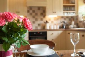 eine Küche mit einem Tisch mit einer Vase Rosen darauf in der Unterkunft Bach y Graig cottage in St Asaph
