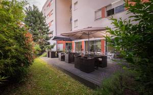 a deck with tables and umbrellas in front of a building at Apparthotel Privilodges Lyon Lumière in Lyon