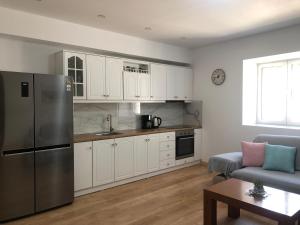 een keuken met witte kasten en een roestvrijstalen koelkast bij Kiparissi Guesthouse in Himare