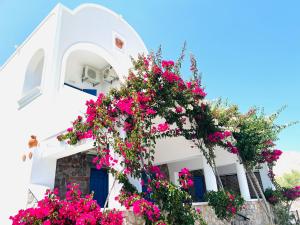 een wit gebouw met roze bloemen erop bij Arapiou Apartments in Perivolos