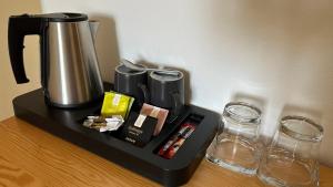 ein Tablett mit einer Kaffeemaschine und Gläsern auf dem Tisch in der Unterkunft Hotel Tynec in Týnec nad Sázavou