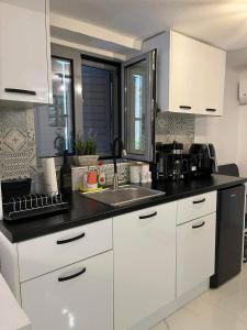 a kitchen with white cabinets and a sink at Riviera-MelRod-Athens in Athens