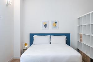a bedroom with a white bed and a blue headboard at RELSTAY - Porta Romana - Large Studio in Milan