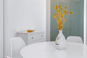 a white table with a white vase with flowers in it at RELSTAY - Porta Romana - Large Studio in Milan