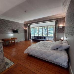 a large white bedroom with a large bed and a couch at Manoir Les Cèdres in Corbehem