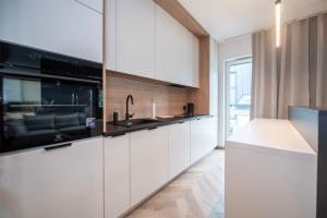 a kitchen with white cabinets and a sink at Apartament Piotrkowska 44 - studio in Łódź