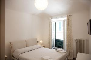 a white bedroom with a bed and a window at Le Caravelle Affittacamere in Genoa