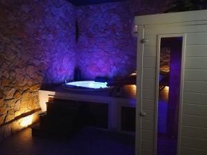 La salle de bains est pourvue d'une baignoire et d'un mur en pierre. dans l'établissement SPA SUITE SICILIA, à Rosolini