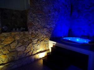SPA SUITE SICILIA في روسوليني: حمام مع حوض استحمام وجدار حجري