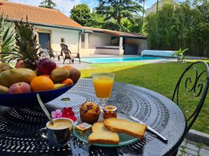 a table with a bowl of fruit and a glass of orange juice at Lyon Faubourg - Saint Priest in Saint-Priest