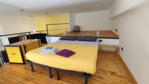 a room with a bed and a yellow table at la casa di amy - loft corvetto in Milan
