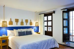 Un dormitorio con una cama blanca con paredes y ventanas azules en AmazINN Places Casa Coyoacan en Ciudad de México