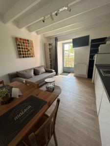 eine Küche und ein Wohnzimmer mit einem Tisch und einem Sofa in der Unterkunft L'escapade, Gîte calme au cœur de Clisson et proche de la Sèvre in Clisson