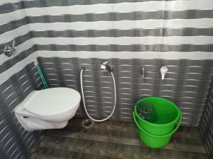 a bathroom with a toilet and a green bucket at Ktm cottage in Kotagiri