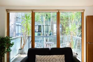 a living room with a couch in front of a large window at The Jasper Walk Escape - Charming 2BDR Flat with Balcony in London