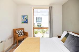 1 dormitorio con cama blanca y ventana en The Jasper Walk Escape - Charming 2BDR Flat with Balcony, en Londres