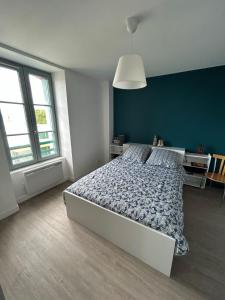 a bedroom with a bed and a blue wall at L'escapade, Gîte calme au cœur de Clisson et proche de la Sèvre in Clisson