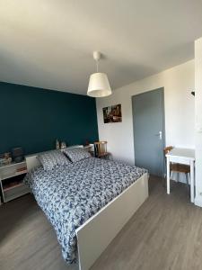 a bedroom with a large bed with a blue wall at L'escapade, Gîte calme au cœur de Clisson et proche de la Sèvre in Clisson