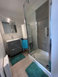 a bathroom with a shower and a sink with green rugs at L'escapade, Gîte calme au cœur de Clisson et proche de la Sèvre in Clisson