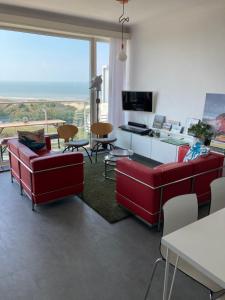 a living room with red furniture and a large window at SEA THE SEA - FEEL THE SEA - TOUCH THE SEA in Bredene