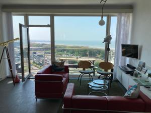 a living room with a couch and a large window at SEA THE SEA - FEEL THE SEA - TOUCH THE SEA in Bredene