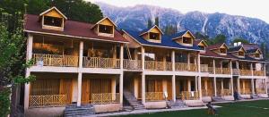 a large building with a mountain in the background at Woodridge Cottages Kalam in Kalām