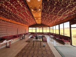 a large room with tables and chairs and windows at Salameh's Bedouin Camp in Wadi Rum