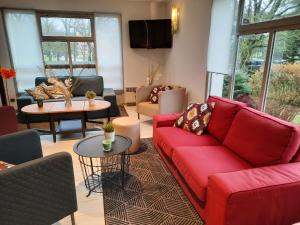 a living room with a red couch and tables at Campanile Metz Est Technopole - Restaurant in Metz