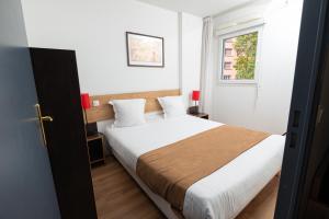 a bedroom with a bed with white sheets and a window at Apparthotel Privilodges Lyon Lumière in Lyon