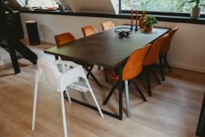 a black dining room table with orange chairs at Boshuisje Rekem - Topo in Lanaken