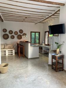 a living room with a kitchen and a tv at Pucci House Watamu in Watamu +65 photos
