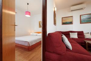 a living room with a red couch and a bed at Guesthouse Aria in Trogir