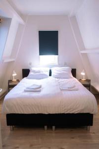 um quarto com uma grande cama branca e 2 candeeiros em 'T Heilige Pad em Egmond aan Zee